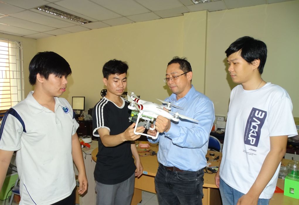TS Nguyễn Đình Uyên (thứ 2 từ phải sang) cùng các bạn trẻ trong lab giới thiệu thiết bị bay không người lái gắn camera quang phổ, cảnh báo thiếu nước trong vườn nông nghiệp. Ảnh: Hà An