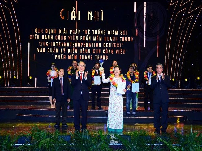 Member of the Politburo, Secretary of HCMC Party Committee Nguyen Thien Nhan (L) awarded cup and certificate of merit to Ms. Pham Thi Kim Phuong - QTSC Deputy CEO, representative of the second prize winner in the field of economy - society, defense - security