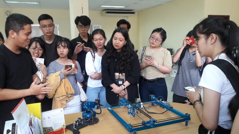 Hình 2: Sinh viên chăm chú xem demo cánh tay robot hỗ trợ việc gieo trồng cây tự động